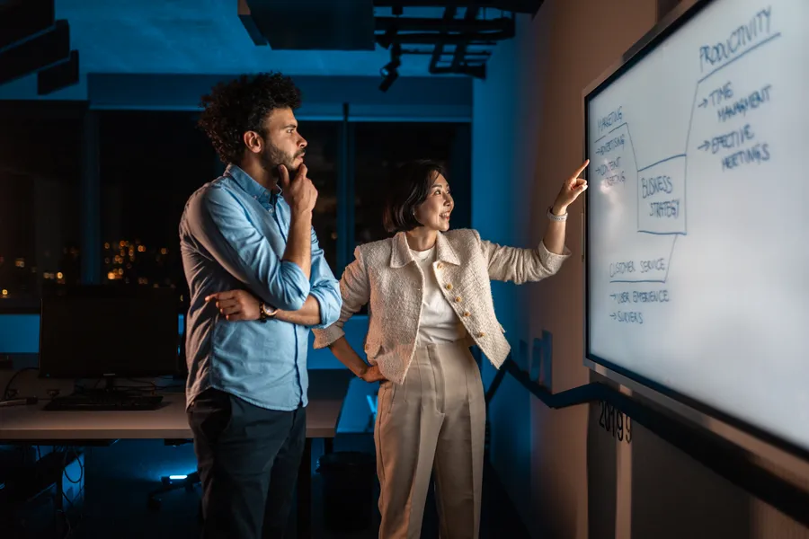 Senior Product Manager in front of whiteboard explaining to team